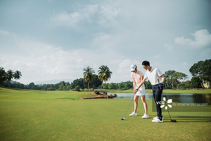 在练习高尔夫的亚洲年轻夫妇图片素材
