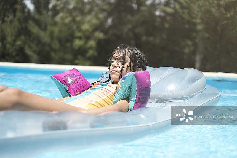 夏天充气垫上戴着耳罩的放松小女孩图片素材