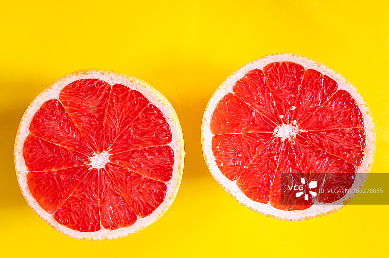 黄色背景上的红色葡萄柚切片图片素材