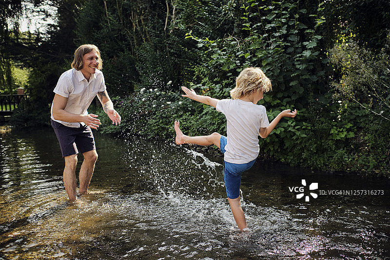 晴天，父子在森林里的小溪中玩耍图片素材
