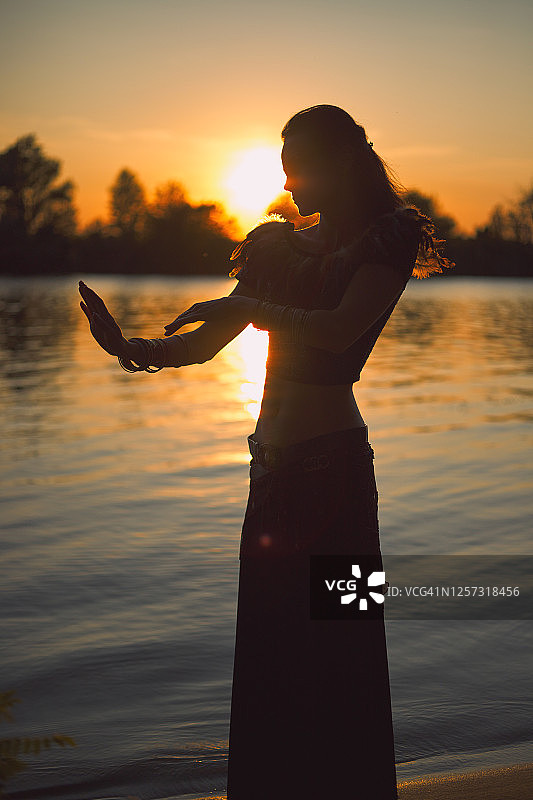 日落时分站在河边的年轻白人女性万圣节符文祭司图片素材