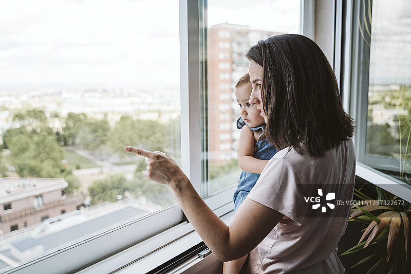 母亲和女婴在家中靠窗户观看图片素材