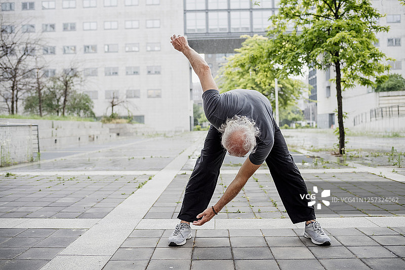 在城市建筑旁的人行道上锻炼的年长男人图片素材