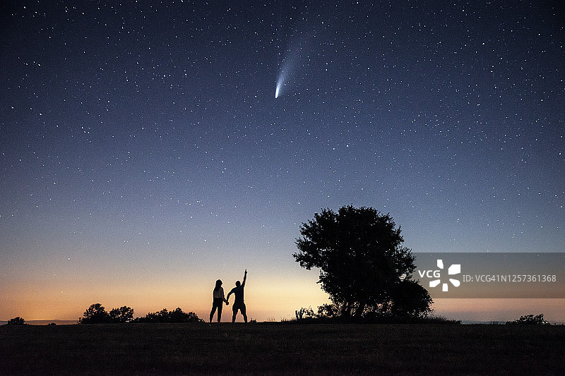 年轻夫妇在明亮的夜空下观看尼欧怀兹彗星图片素材