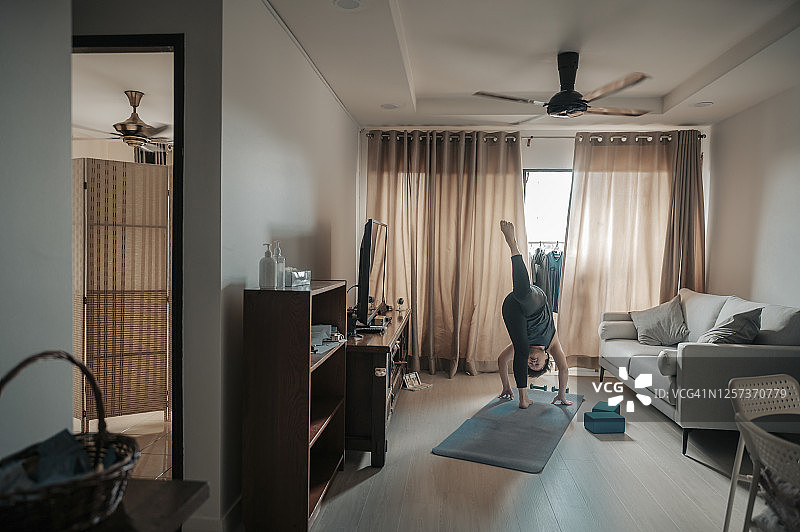 一位中国中年女子在客厅练习瑜伽图片素材