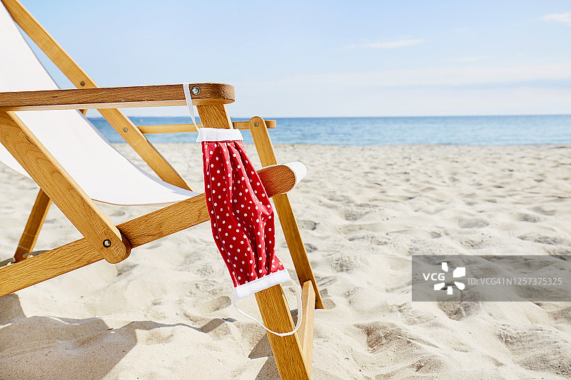 海滩躺椅上悬挂的自制红色口罩图片素材