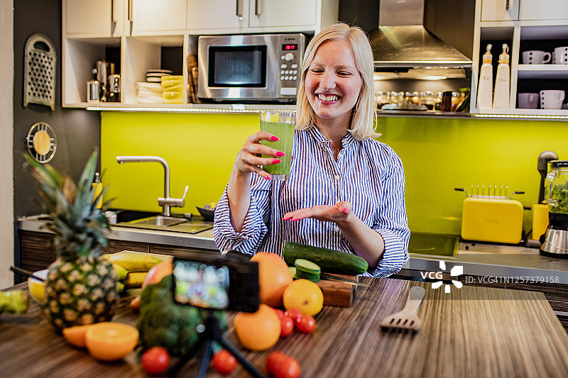 年轻女人拍摄关于健康烹饪的视频博客图片素材