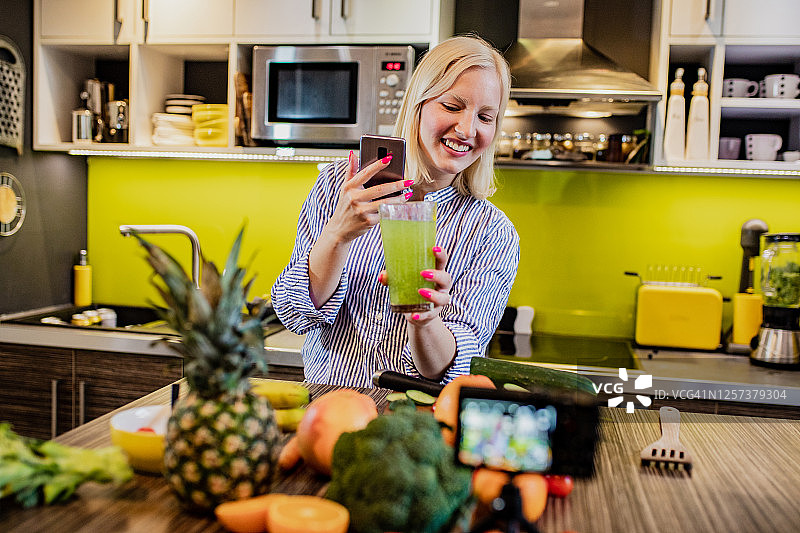 年轻女人拍摄关于健康烹饪的视频博客图片素材