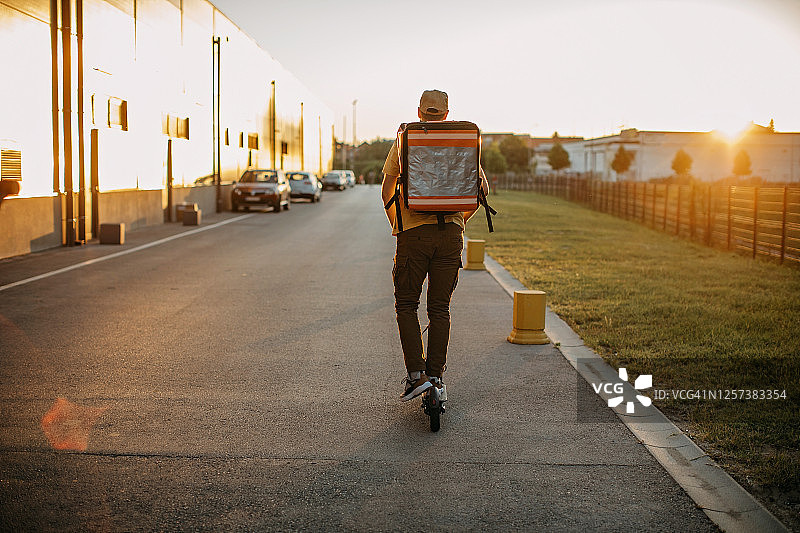 快递员骑电动滑板车派送包裹图片素材