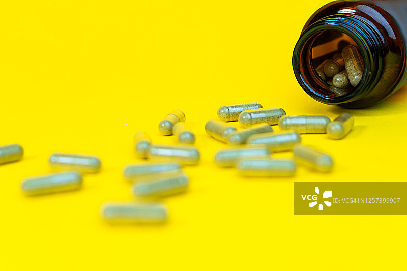 黄色背景下的维生素D胶囊瓶图片素材