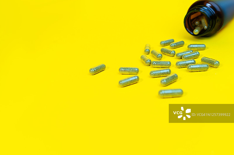 黄色背景下的维生素D胶囊瓶图片素材