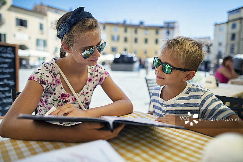 姐弟在卢卡街头餐厅享用披萨午餐图片素材