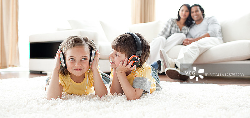 小男孩和小女孩戴着耳机在地板上玩耍图片素材
