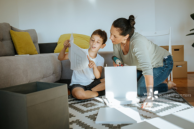 男孩和母亲按照组装说明制作书架图片素材