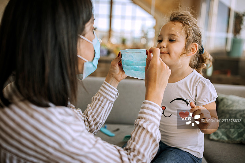 母亲为女儿戴上防护口罩图片素材