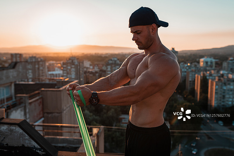 在楼顶用阻力带锻炼的男人图片素材