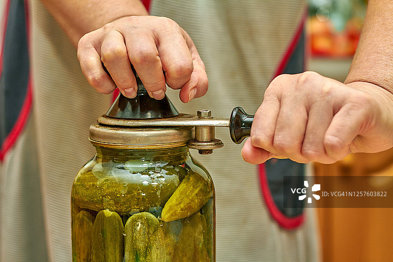 用卷边机将新鲜的家用黄瓜保存在玻璃罐中：特写，选择性聚焦图片素材