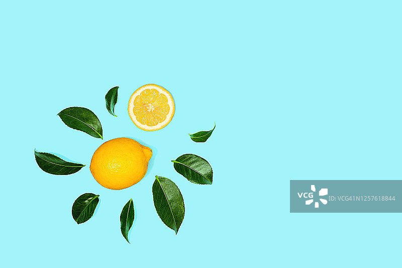 蓝色背景上的柠檬柑橘和绿叶热带图案图片素材