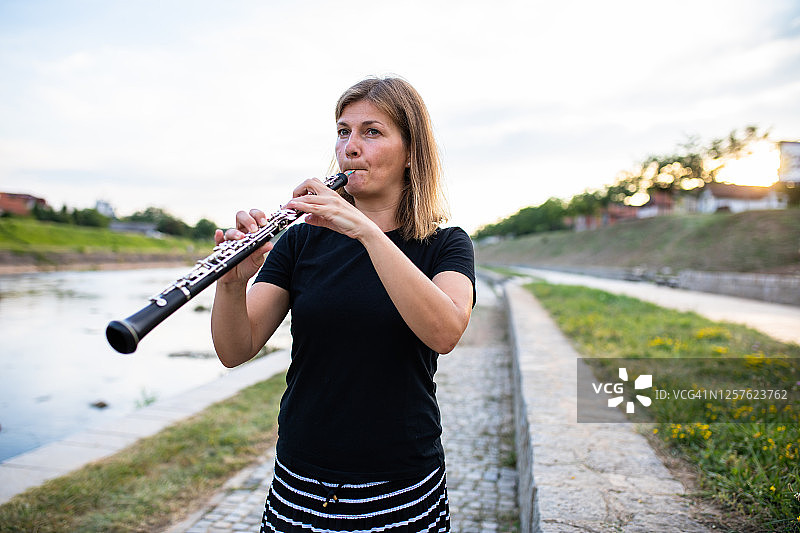 一位女双簧管演奏者在河边演奏双簧管图片素材