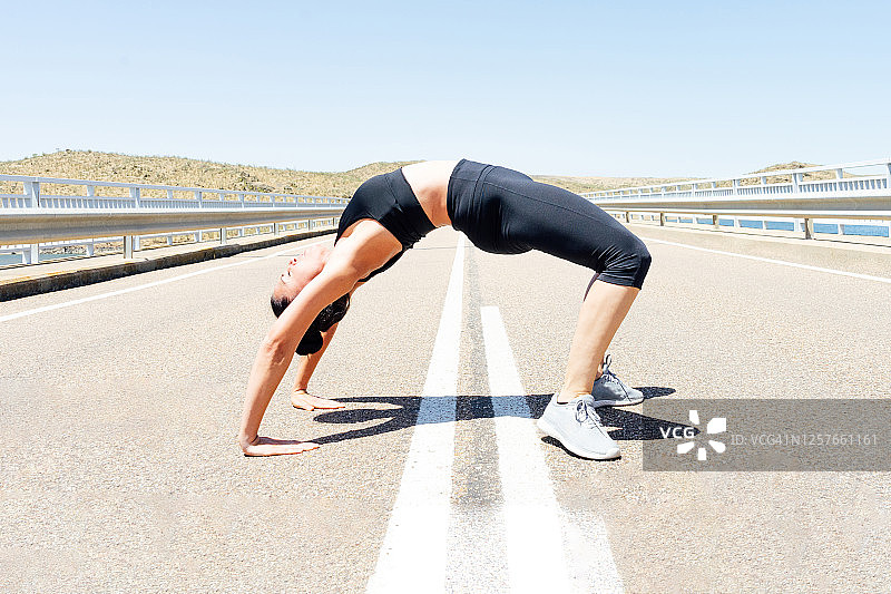 年轻男子在城市道路上练习瑜伽，做桥式运动-档案照片图片素材