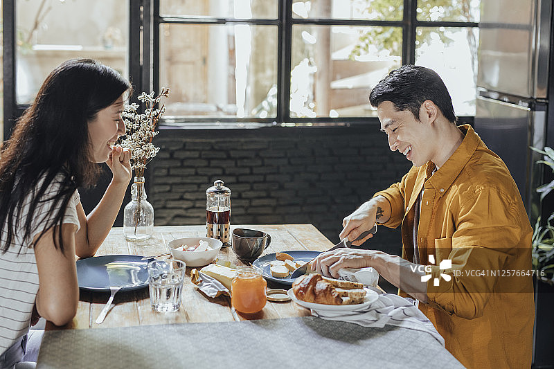 快乐亚洲情侣在家享用欧式早餐图片素材