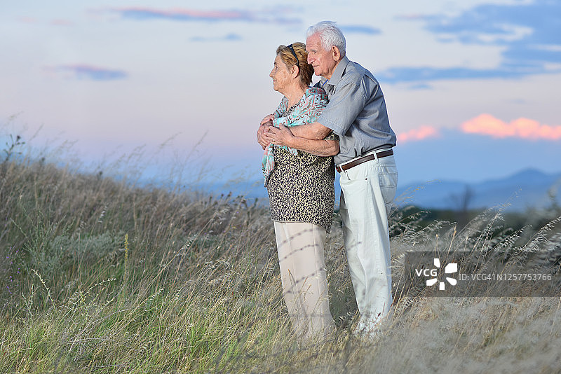 在山顶美丽日落时相爱的健康年长夫妇图片素材