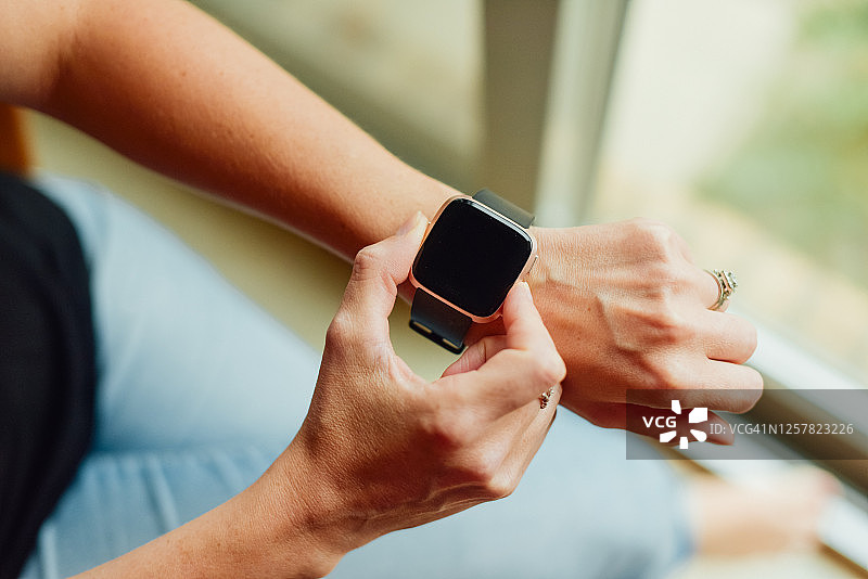 年轻白人女性手腕上戴着智能手机图片素材