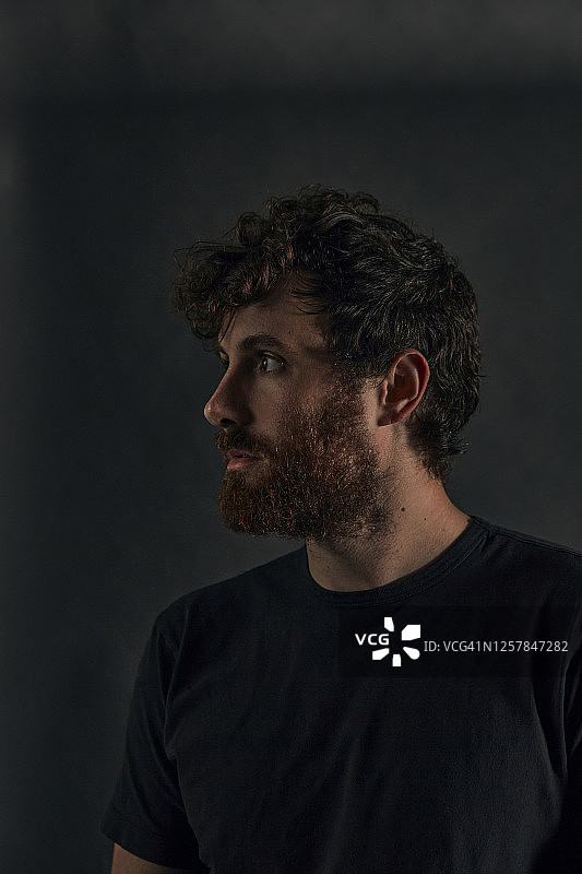 深色影棚人像：侧身看向镜头外的男人图片素材