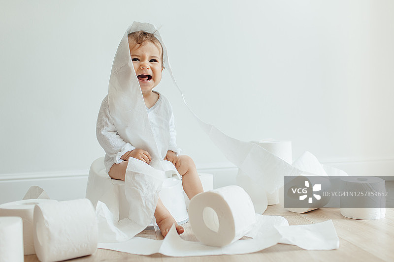 坐在白色便盆上哭泣的可爱小孩图片素材