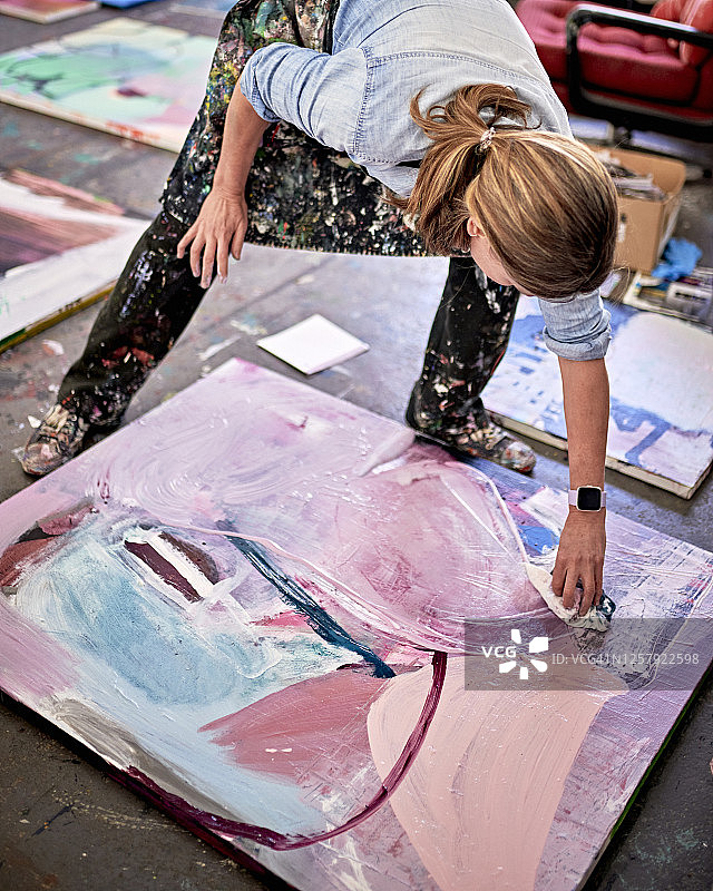 在绘画工作室用抹布涂抹画作的女艺术家图片素材