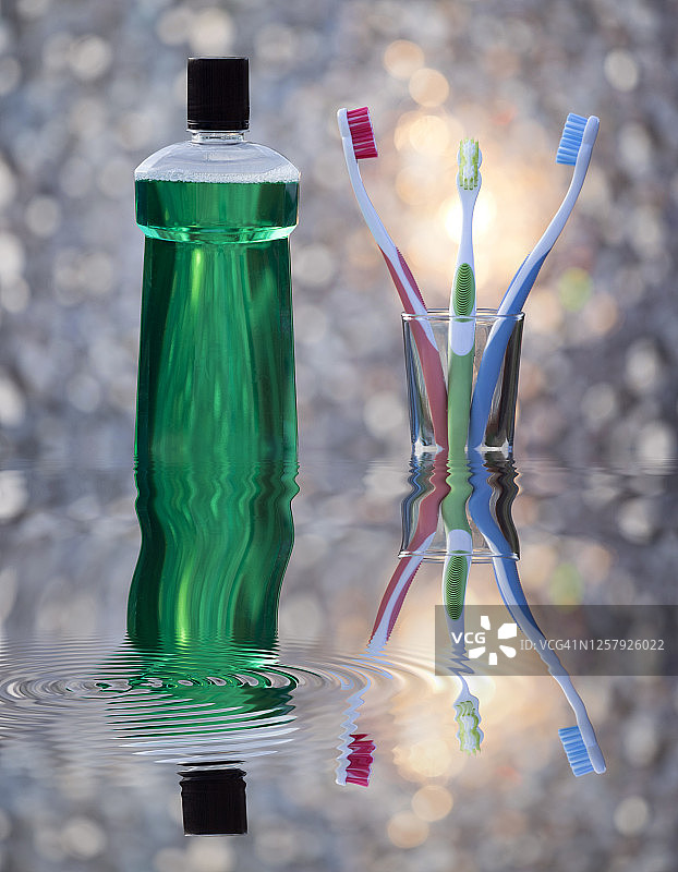 牙科漱口水瓶和玻璃杯，牙刷倒映在水中图片素材