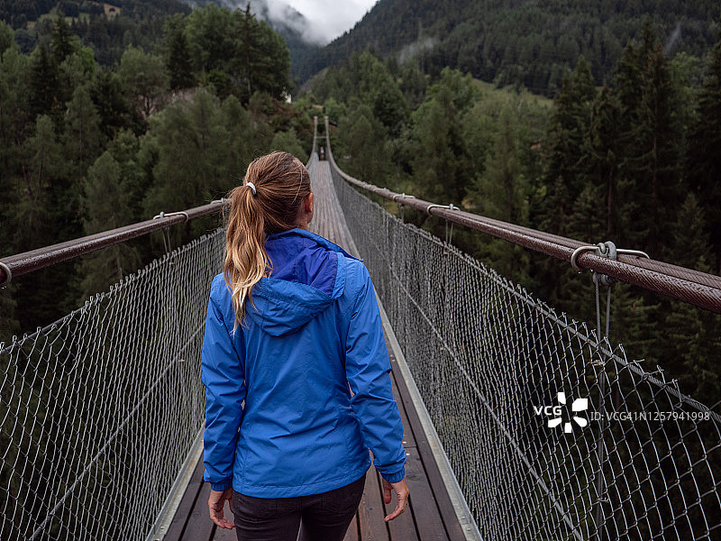 在瑞士松树谷上方吊桥上行走的女人图片素材