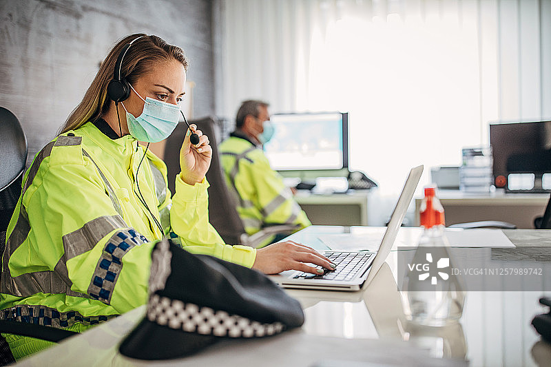 在办公室戴着防护口罩工作的男女警察图片素材
