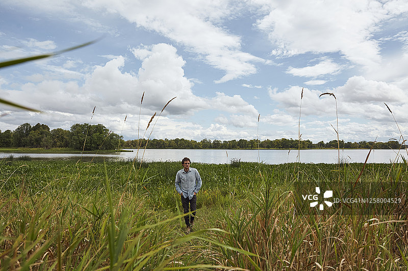 一个男人走向镜头，身后是湖图片素材