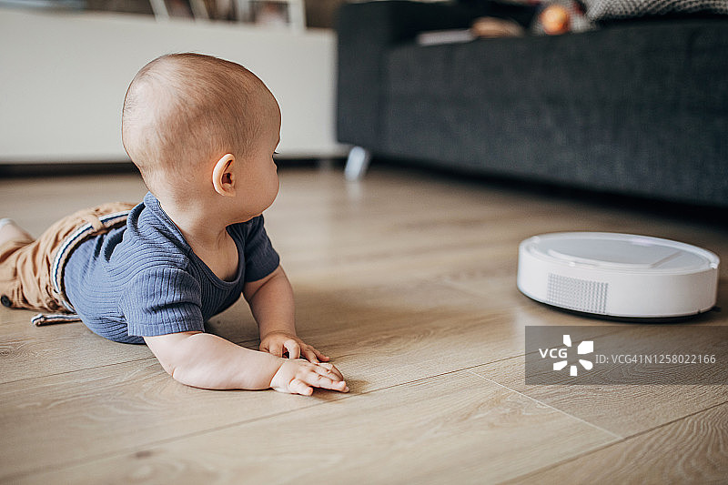可爱的男婴探索扫地机器人图片素材