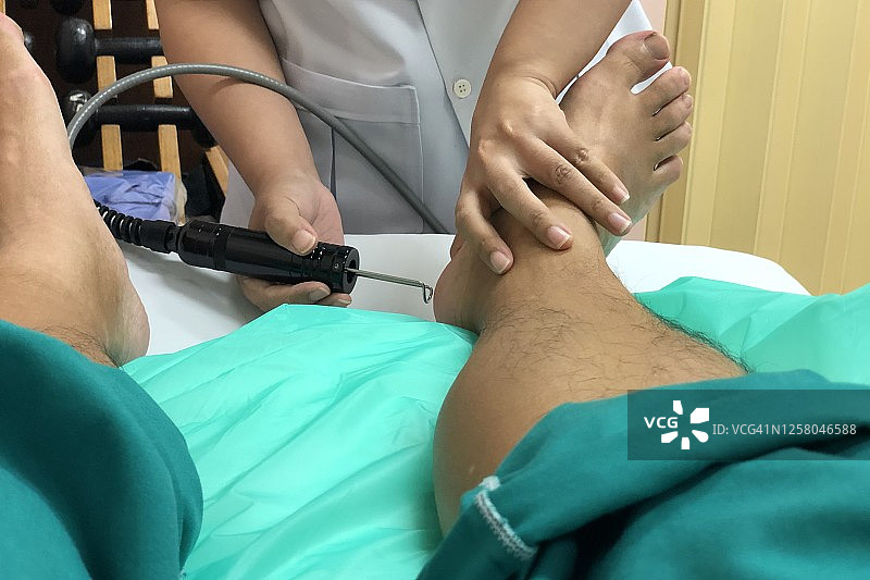在医疗康复诊所，使用医疗激光治疗足底筋膜炎引起的足部疼痛图片素材