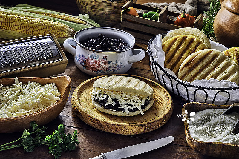 委内瑞拉传统食物：夹着碎奶酪和黑豆的阿瑞巴（Domino）。乡村厨房桌子上的食材。图片素材