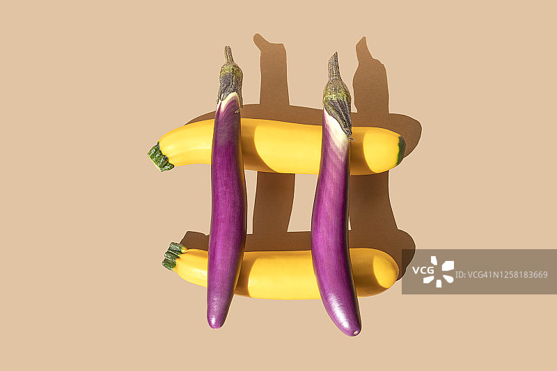 金色西葫芦和紫色茄子在米色背景上组成井号图片素材