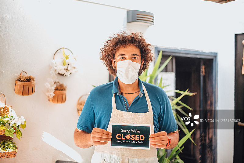 疫情后小企业里男人拿着已关闭的牌子图片素材