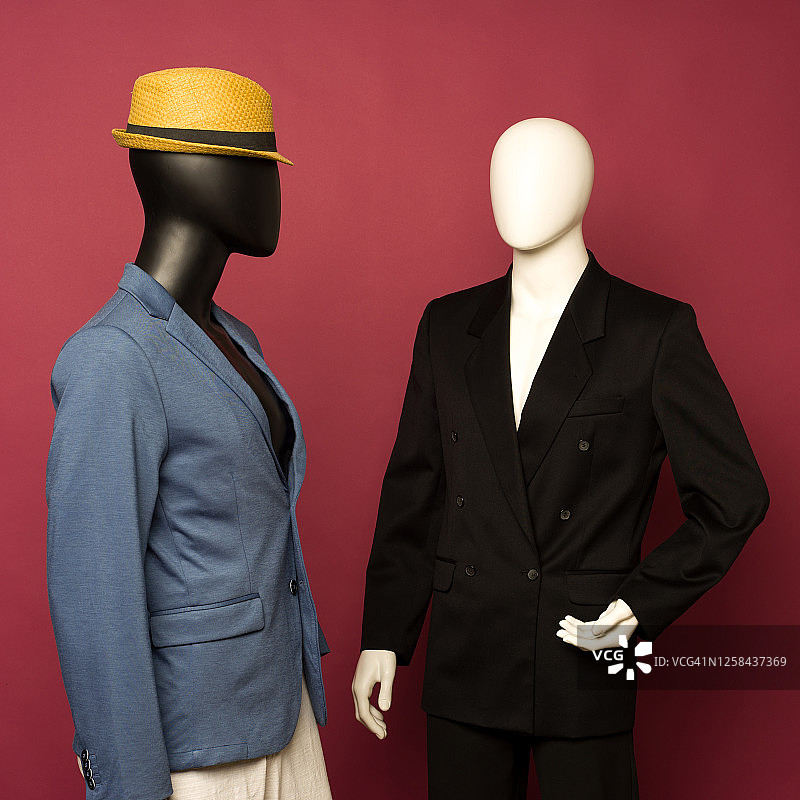 红宝石背景上的黑色商务套装和蓝色套装白色裤子的两个男士人体模型图片素材
