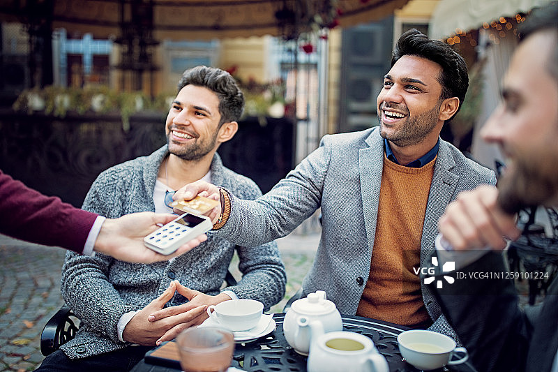 朋友们在自助餐厅使用非接触式信用卡付款图片素材