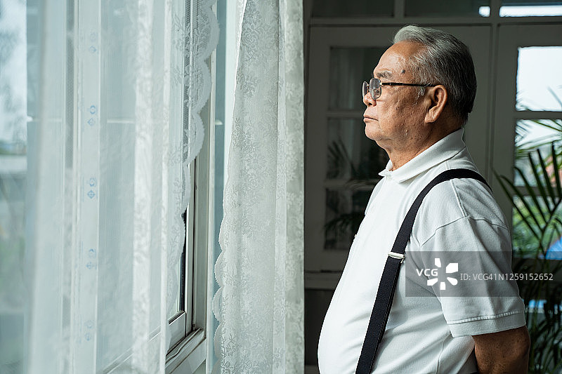 戴眼镜的沉思老人望着窗外，感到孤独的特写图片素材