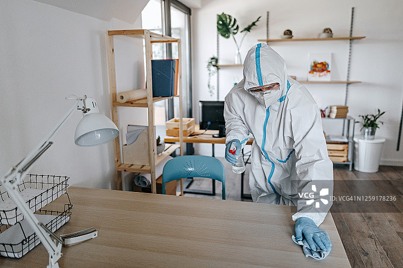 穿防护服的男人在办公室消毒图片素材