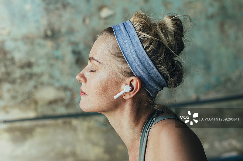 金发女人戴着无线耳机在线收听冥想指导特写图片素材