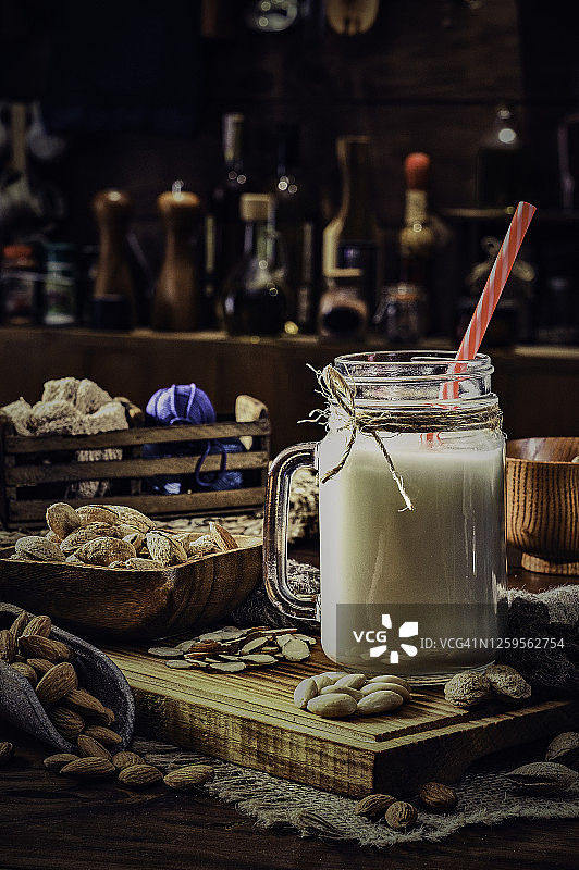 老式乡村厨房中装在玻璃杯和罐子里的非乳制杏仁奶和坚果图片素材