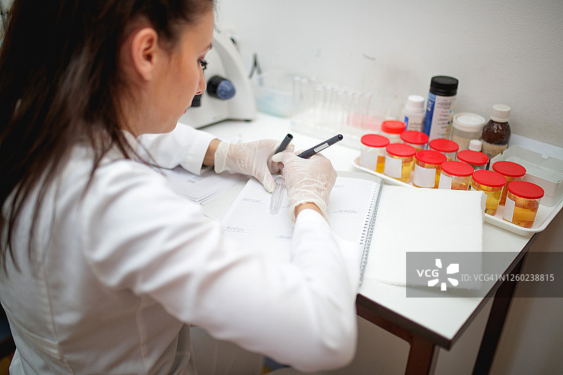 实验室技术员戴着防护手套在空试管上写号码图片素材