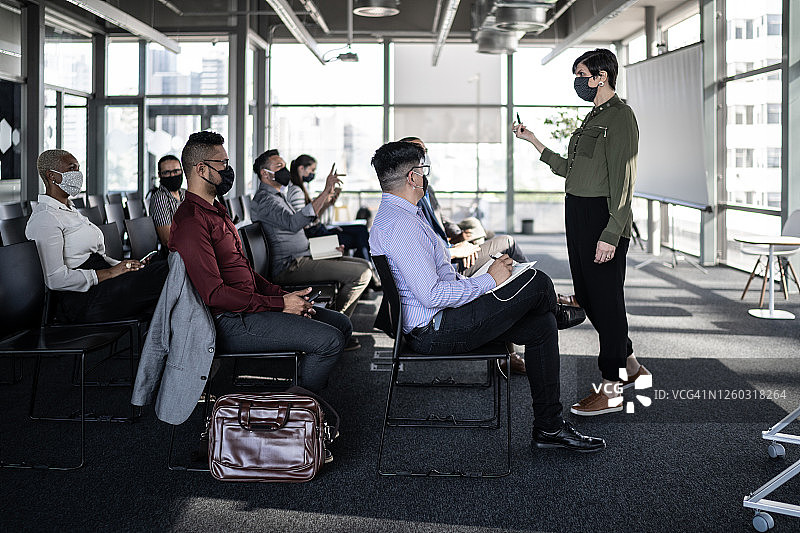 佩戴口罩保持社交距离参加研讨会的商人图片素材