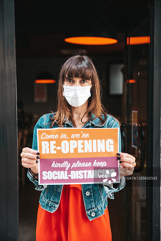 疫情后手持“营业中”标牌的小商店店主图片素材