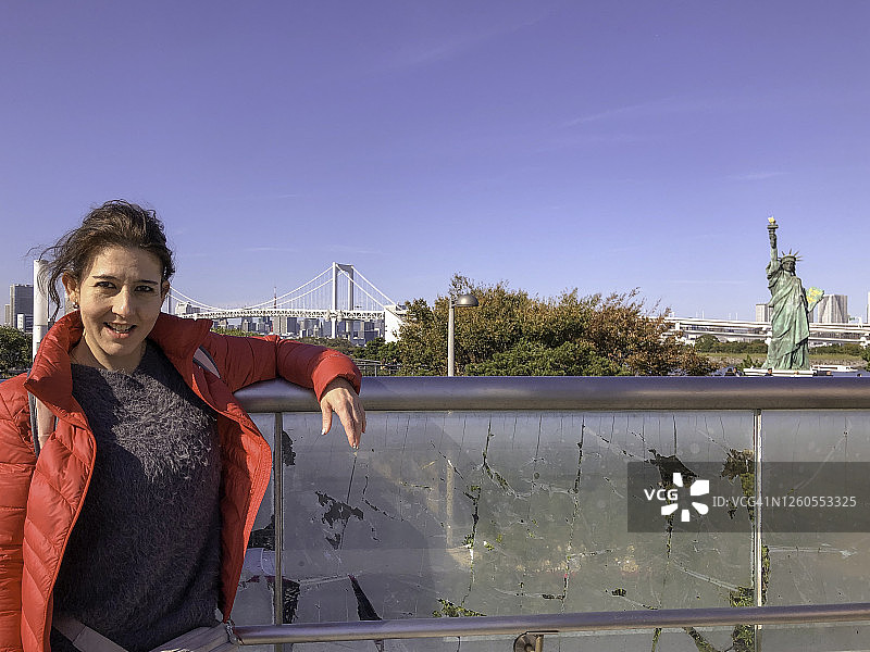 在御台场海滨公园自由女神像复制品前摆姿势的美国女人图片素材
