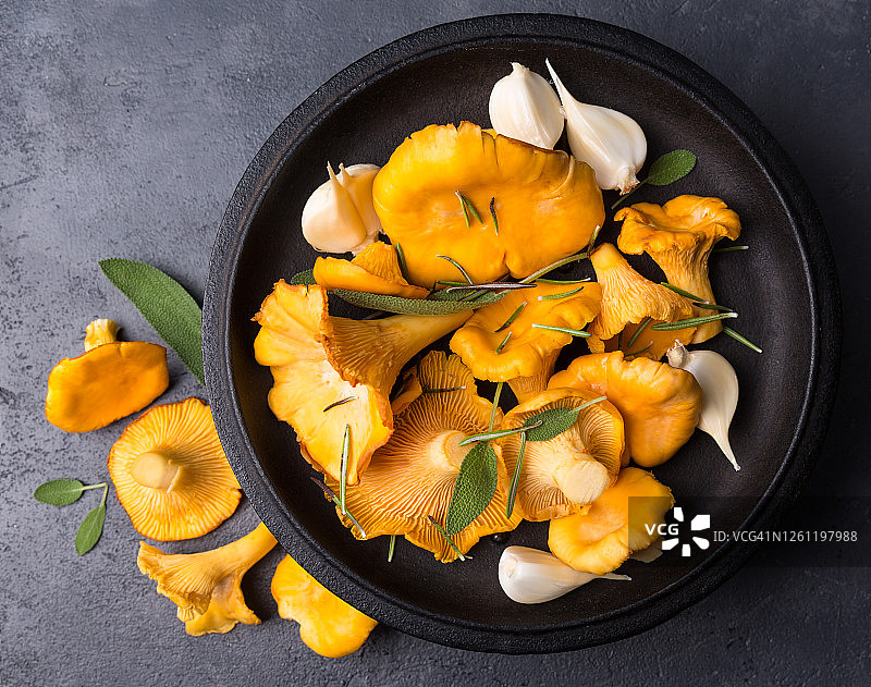 未经烹煮的野生鸡油菌及香料和香草，可用于烹饪，黑色背景上的野生蘑菇图片素材